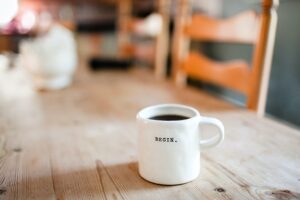 A coffee mug full of black coffee. Words on the mug say "Begin"